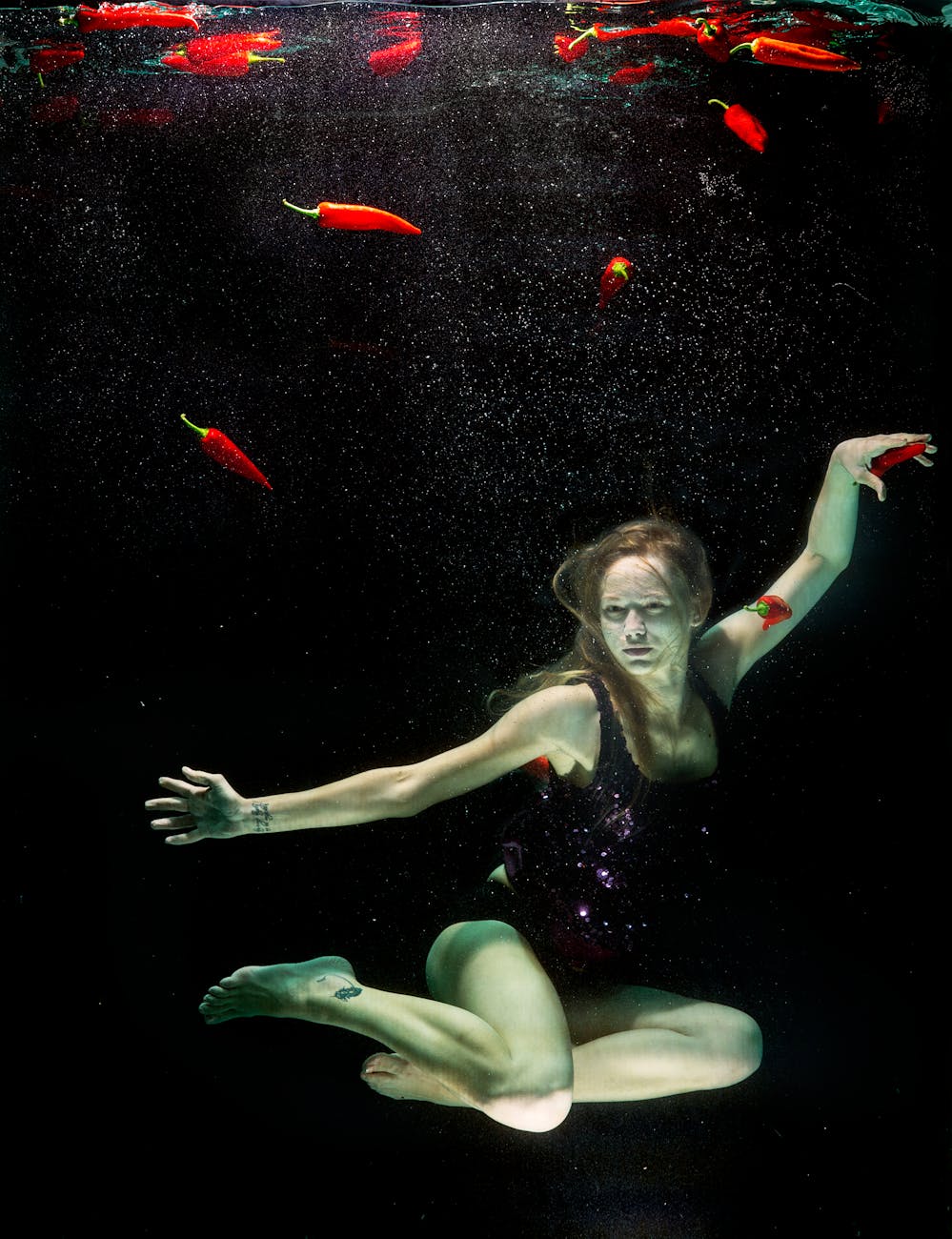 Woman in a calm, fluid motion pose against a dark background.